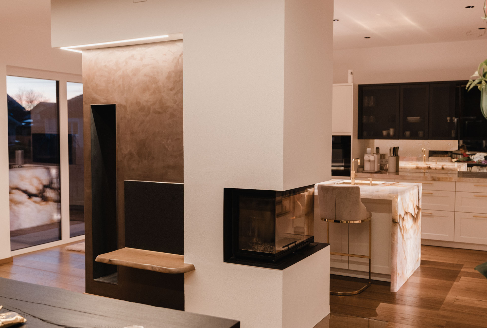 heller Innenraum mit dunklem Holzboden, sichtbaren Dachbalken und freistehendem Kamin